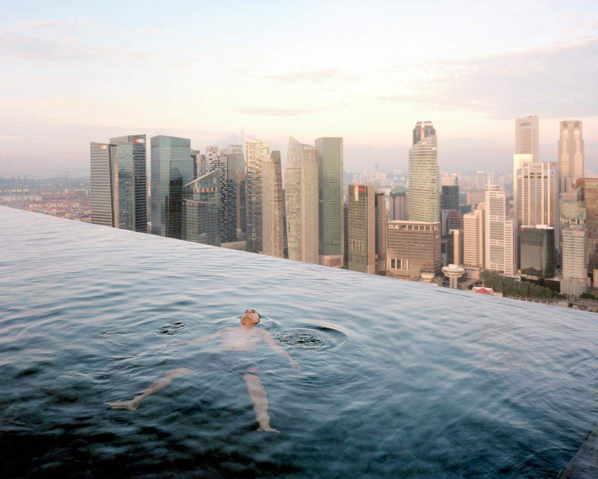 Ein Mann im Pool des "Marina Bay Sands Hotel" in Singapur - hinter ihm der Finanzbezirk der Stadt. (Paolo Woods, 2013)