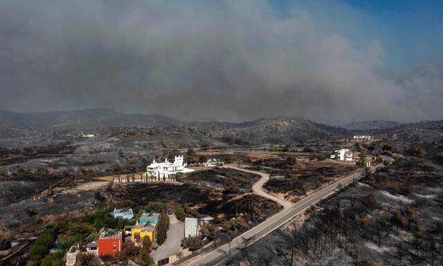 Eine Luftaufnahme zeigt Rauchschwaden im Hintergrund des Dorfes Kiotari auf der Insel Rhodos am 24. Juli 2023. Zehntausende von Menschen sind bereits vor den Bränden auf der Insel Rhodos geflohen.