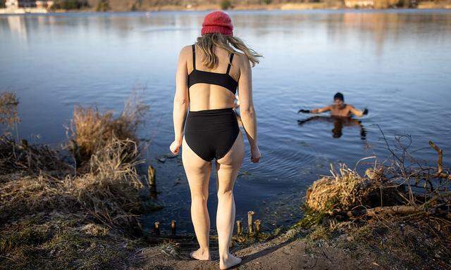 Woman going for a swim in lake on a winter day