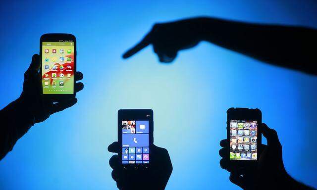 Men pose with Samsung Galaxy S3 Nokia Lumia 820 and iPhone 4 smartphones in photo illustration in Zenica