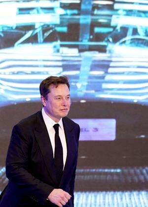 FILE PHOTO: Tesla Inc CEO Elon Musk walks next to a screen showing an image of Tesla Model 3 car during an opening ceremony for Tesla China-made Model Y program in Shanghai