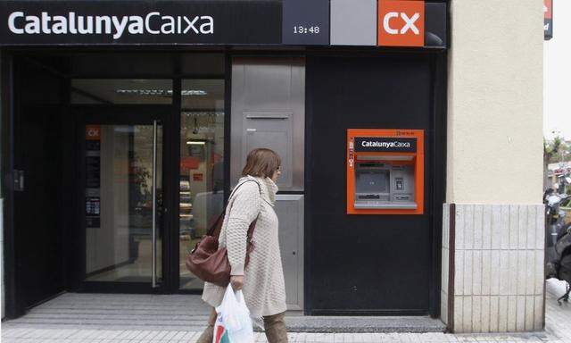 A woman walks outside a branch of nationalized savings bank Catalunya Caixa in Vilassar de Mar