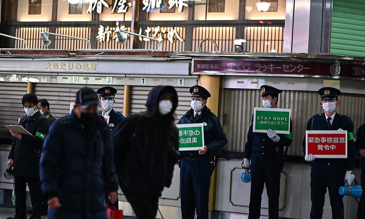 Polizisten weisen in Tokio Passanten darauf hin, wegen der Corona-Pandemie wenn möglich zu Hause zu bleiben.