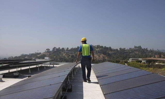 Arbeiter überprüft Solaranlagen auf einem Dach in Los Angeles, USA.