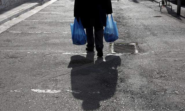 A man carries bags which were distributed to him during a donation program of the municipality of Athens