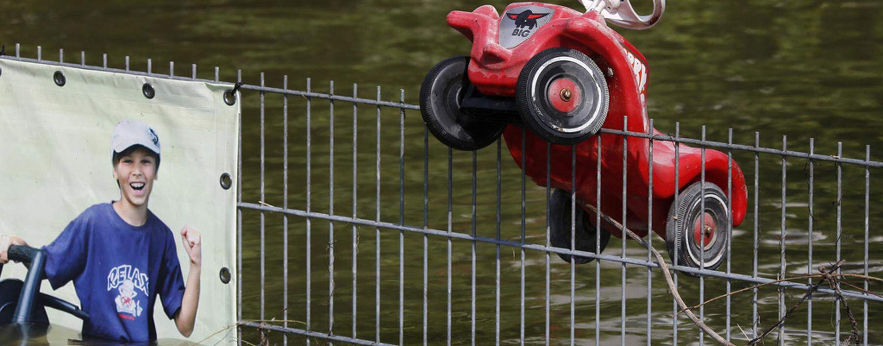 A toy vehicle hangs on a fence along a flooded street in Fischerdorf