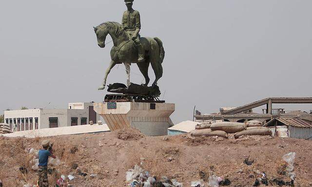 Ein kudischer Kämpfer feuert auf eine Statue von Bassel al-Assad, dem Bruder des syrischen Präsidenten.