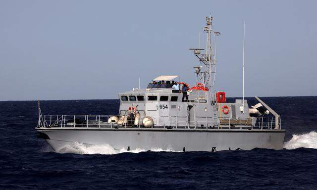 A Libyan coast guard vessel powers next to former fishing trawler Golf Azzurro of the Proactiva Open Arms rescue charity in the Western Mediterranean Sea