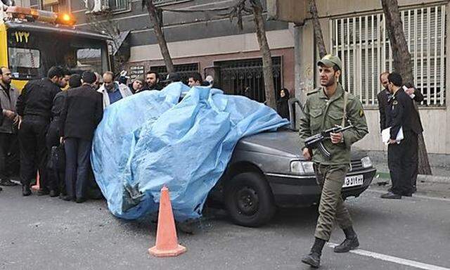 A policeman walks past the car belonging to Iranian nuclear scientist Mostafa Ahmadi-Roshan at a blas