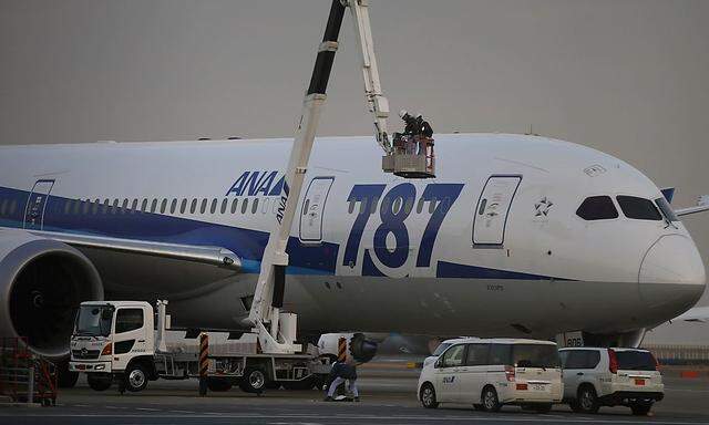 ANA mechanics work beside the company's Boeing Co's 787 Dreamliner plane at Haneda airport in Tokyo