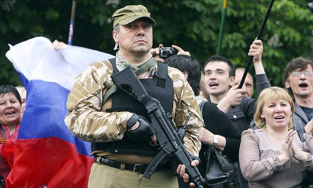 A bodyguard hold his weapon during a rally to mark and celebrate the announcement of the results of the referendum on the status of Luhansk region in Luhansk
