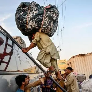 Flüchtlinge laden ihre Habseligkeiten auf einen Bus, der sie aus Pakistan nach Afghanistan bringen soll.