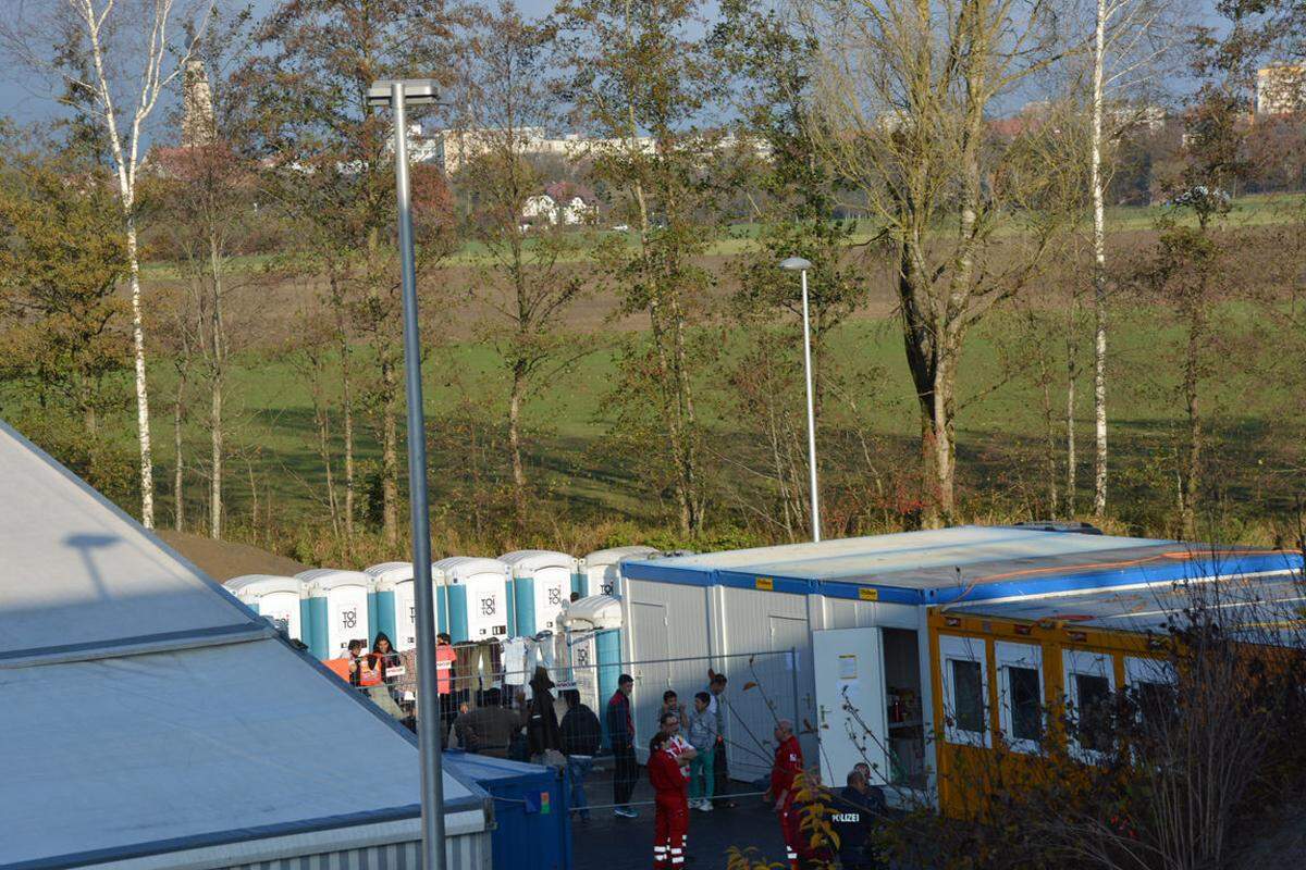 Zuvor waren die Menschen in der Stadt untergebracht worden, bevor sie die Innbrücke passieren konnten. Nun warten sie etwas außerhalb, direkt neben dem zweiten Grenzübergang auf die Busse nach Deutschland, die stündlich 50 Personen in die bayerische Stadt Simbach bringen.