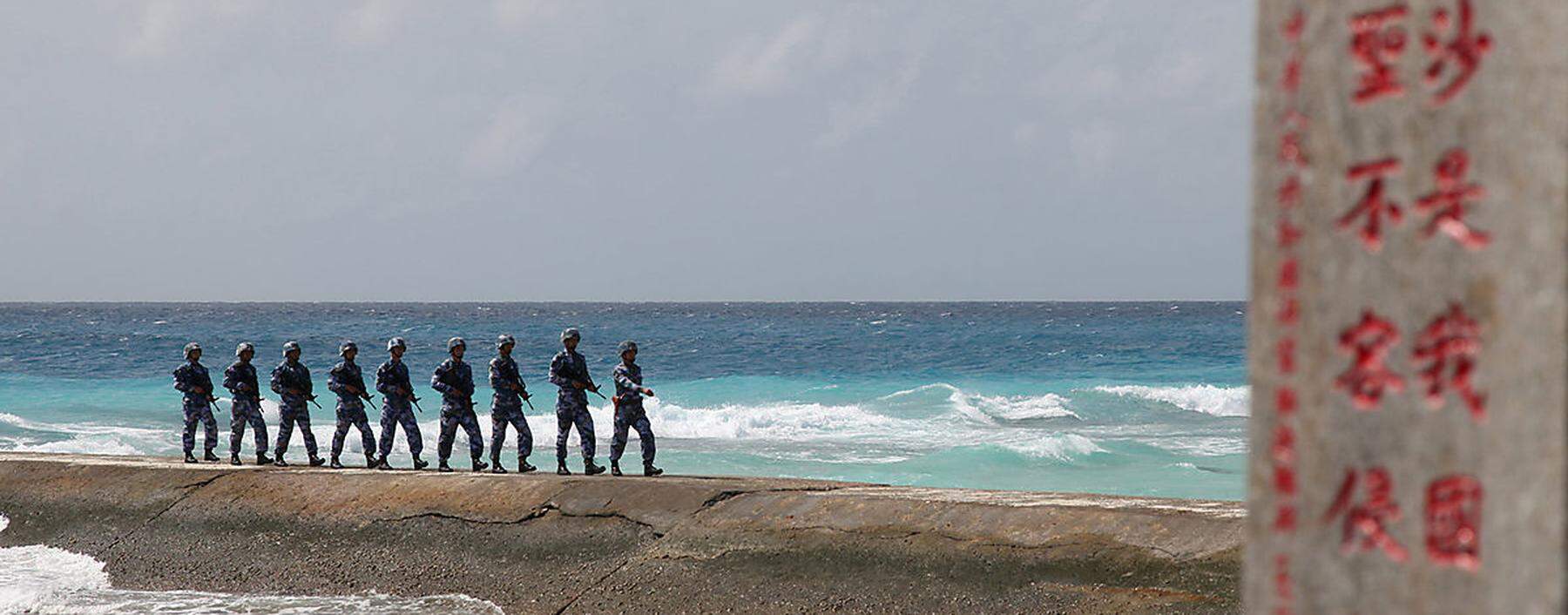 Soldiers of China´s People´s Liberation Army (PLA) Navy patrol near a sign in the Spratly Islands, known in China as the Nansha Islands