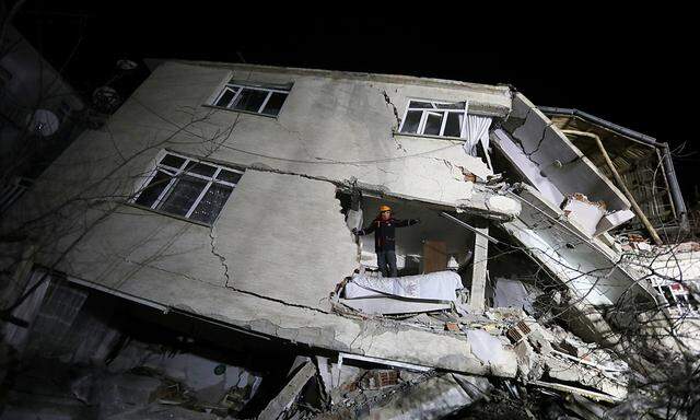 A rescue worker stands on a collapsed building after an earthquake in Elazig