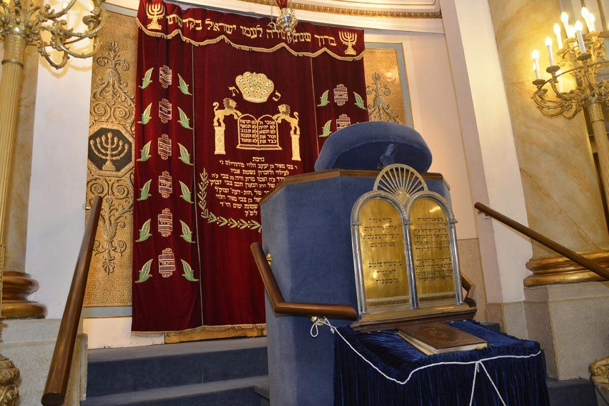 Hinter dem roten Samtvorhang werden die Tora-Rollen aufbewahrt, die den fünf Büchern Mose im alten Testament der Bibel entsprechen. Die jüdische Glaubenslehre wird ergänzt durch den Talmut, der viele der jüdischen Traditionen beschreibt.