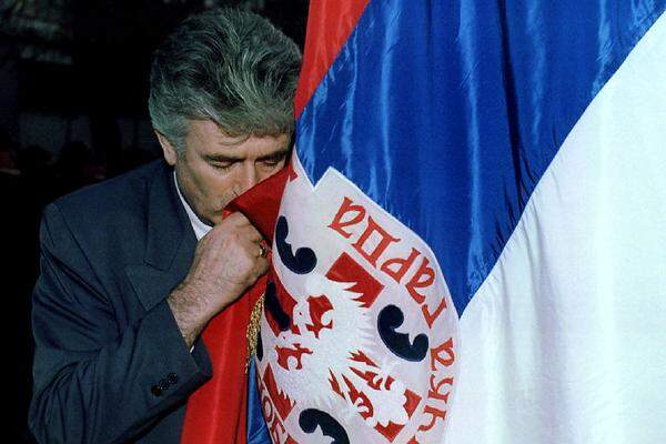 Im April 1992 erkennen die EG-Staaten erkennen Bosnien und Herzegowina als eigenen Staat an. Zuvor haben die Muslime und Kroaten in einem von den Serben boykottierten Referendum für die Unabhängigkeit gestimmt. Die Belagerung von Sarajevo beginnt, sie wird erst am 29. Februar 1996 für beendet erklärt. Die bosnisch-serbische Armee unter dem Kommando von Ratko Mladic erobert in kurzer Zeit 70 Prozent des Landes. Bild: Karadzic küsst die Flagge der berüchtigten Tiger-Miliz des Warlords "Arkan" aus Serbien. Sie kämpfen an der Seite der bosnischen Serben.