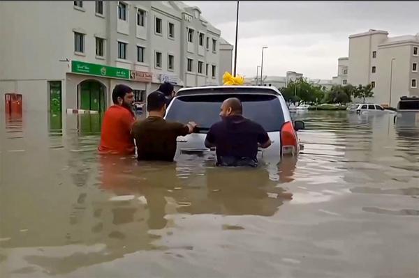 Menschen in Dubai versuchen, ihr Auto aus den Wassermassen zu retten.