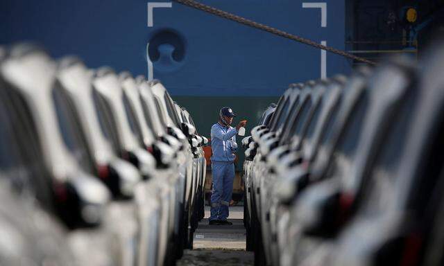 A worker cleans new cars before they are loaded onto a cargo ship for export at the Tanjung Priok Car Terminal in Jakarta