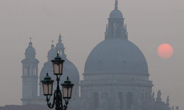 Sunset is seen behind of the ´Madonna della Salute´ church in the Venetian lagoon, Italy