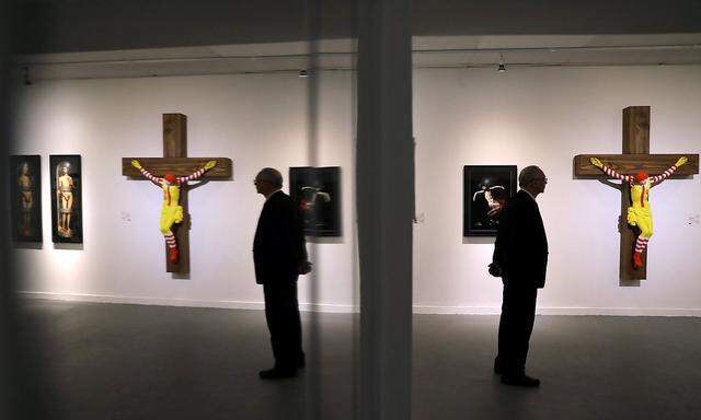 A man stands next to a sculpture by Finnish artist Jani Leinonen, entitled 'McJesus', is seen on display at Haifa Museum of Art in the northern Israeli city of Haifa