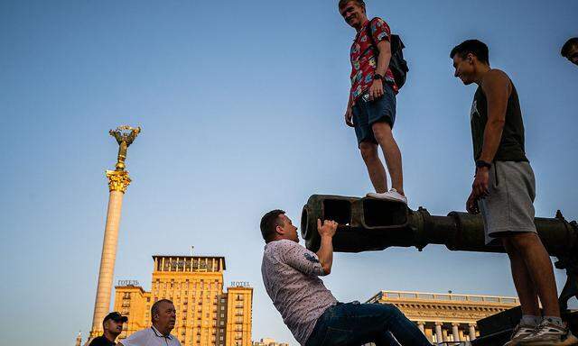 Auf diesem Foto vom 21. August 2022 klettern Menschen auf ein zerstörtes russisches Kriegsfahrzeug auf dem Kiewer Unabhängigkeitsplatz "Maidan", der im Vorfeld des ukrainischen Unabhängigkeitstages am 24. August in ein Freilicht-Militärmuseum umgewandelt wurde.