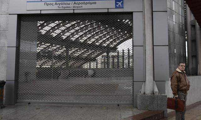 A commuter stands outside a closed metro station during a 24-hour strike of workers at the Athens Metro, tram, suburban railway and city train in Athens