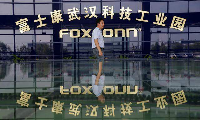 A man walks past a logo of a Foxconn factory in Wuhan
