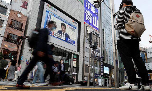 A large screen on a building shows live broadcast of Japan's Prime Minister Shinzo Abe's news conference at Shinjuku district in Tokyo