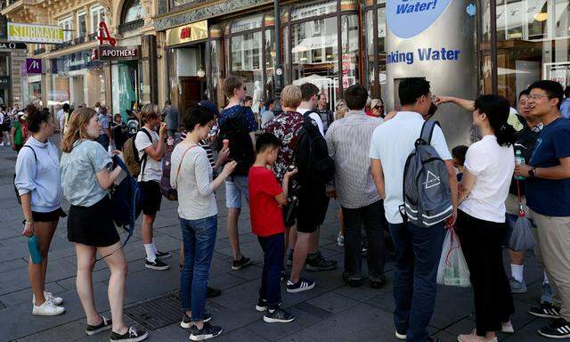 Tourists queue to get water during a heat wave in the city center of Vienna