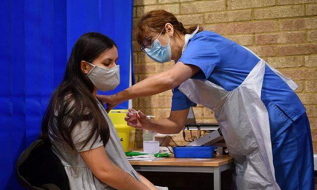 A nurse administers the Pfizer/BioNTech COVID-19 vaccine to a woman at a vaccination centre in Cardiff