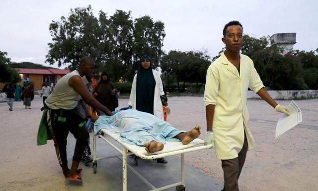 Paramedics and civilians carry an injured person on a stretcher at Madina hospital after a blast at the Elite Hotel in Lido beach in Mogadishu