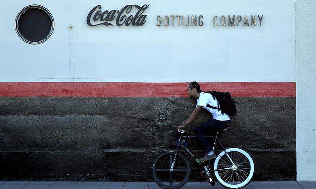 FILE PHOTO: A man cycles past the Coca Cola bottling plant in Los Angeles
