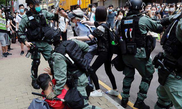 Anti-government demonstrators scuffle with riot police during a lunch time protest as a second reading of a controversial national anthem law takes place in Hong Kong