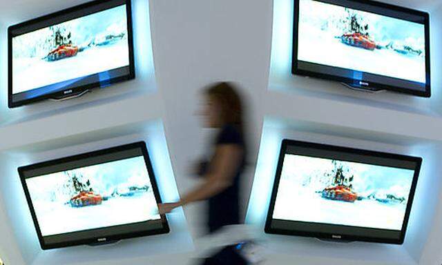 A woman walks in front of television screens of Philips in preparation of IFA, the worlds largest trs largest tr