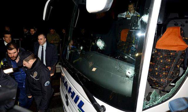 Police officers, team officials and journalists surround the damaged Fenerbahce team bus which was shot at while it was being driven through to Trabzon Airport in the Black Sea coastal province of Trabzon