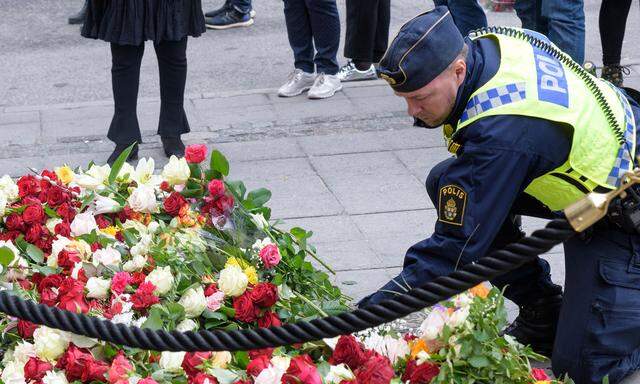 Ein Polizist legt Blumen in der Nähe des Tatortes in Zentral-Stockholm nieder. 