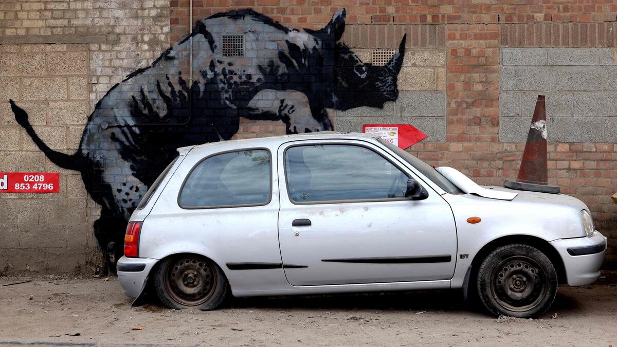 TOPSHOT - An artwork by street artist Banksy, the eighth to released in eight days, depicts a rhino mounting a car, on a wall in Charlton, London, on August 12, 2024. The artist confirmed the work to be theirs after posting an image of it on the social media app Instagram. (Photo by Adrian DENNIS / AFP) / RESTRICTED TO EDITORIAL USE - MANDATORY MENTION OF THE ARTIST UPON PUBLICATION - TO ILLUSTRATE THE EVENT AS SPECIFIED IN THE CAPTION