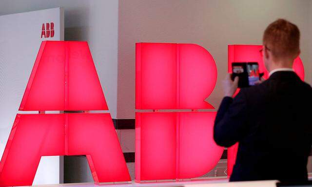 FILE PHOTO: Man takes pictures of logo of Swiss power technology and automation group ABB ahead of a news conference to present full year results in Zurich