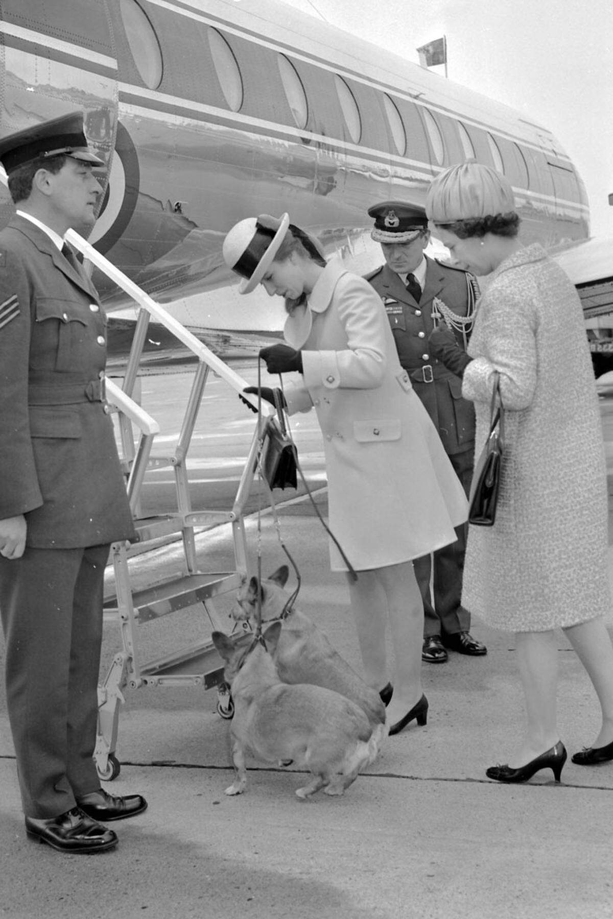 Auch auf Reisen der Queen müssen die Hunde immer dabei sein. So sind einige Bedienstete des Hauses exklusiv für die Betreuung der Corgis und Dorgis zuständig. "Nach dir": Queen Elizabeth und ihre Tochter Prinzessin Anne am Londoner Flughafen Heathrow, Mai 1969.