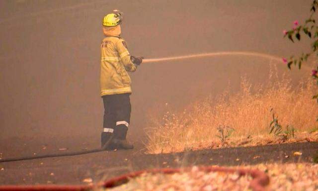 Dieser Ausschnitt aus einem Video, das von der Australian Broadcast Corporation (ABC) am 21. Dezember 2023 zur Verfügung gestellt wurde, zeigt Feuerwehrleute im Vorort Parkerville, östlich von Perth, bei dem Versuch, ein Buschfeuer zu löschen. 