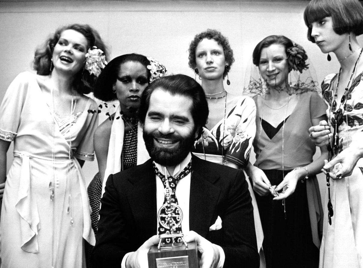 Karl Lagerfeld 1973 inmitten von Models mit einer Auszeichnung in der Hand.
