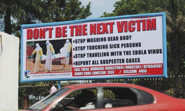 A car drives past a public health advertisement against the Ebola virus in Monrovia