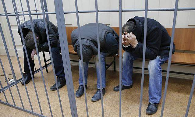 Unidentified suspects, detained over the killing of Boris Nemtsov, hide their faces inside a defendants´ cage as they attend a court hearing in Moscow