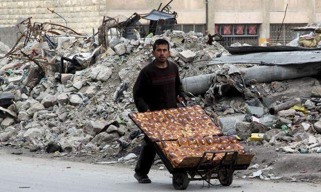 A man selling pastries walks past the rubble of damaged buildings in the rebel held al-Shaar neighborhood of Aleppo
