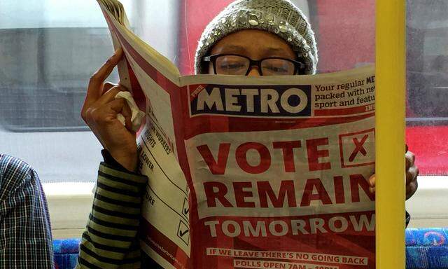 A woman reads a newspaper on the underground in London with a ´vote remain´ advert for the BREXIT referendum