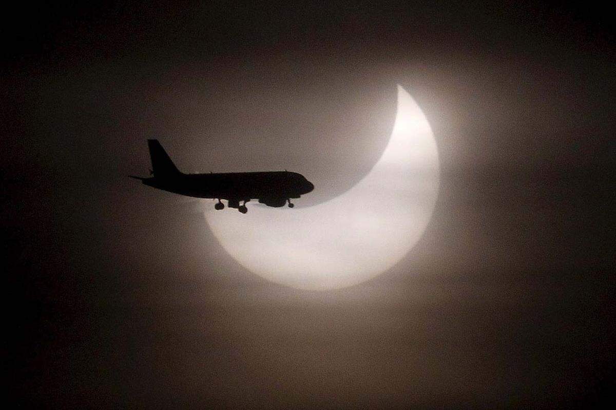 Ein Flugzeug passiert nahe von Barcelona die Sonneneklipse.