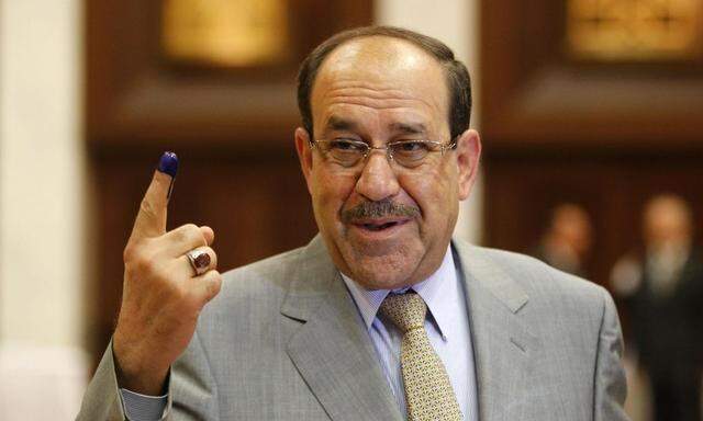 Nuri al-Maliki shows his ink marked finger as he votes during parliamentary election in Baghdad