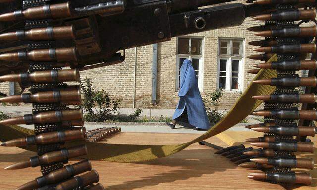 An Afghan woman walks inside a police compound as former Afghan Taliban members hand over their weapons after joining the Afghan government´s reconciliation and reintegration programme in Herat