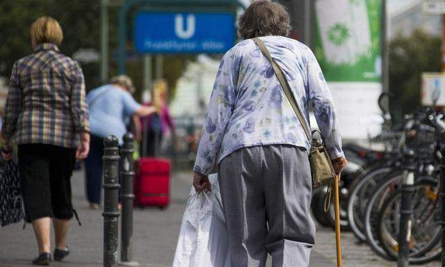 Elderly woman walks on stick along shopping street in Berlin